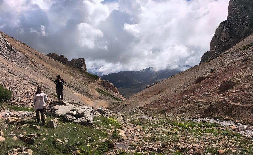 Travelers in vast mountain valley with cloud-capped peaks, China butterfly expedition